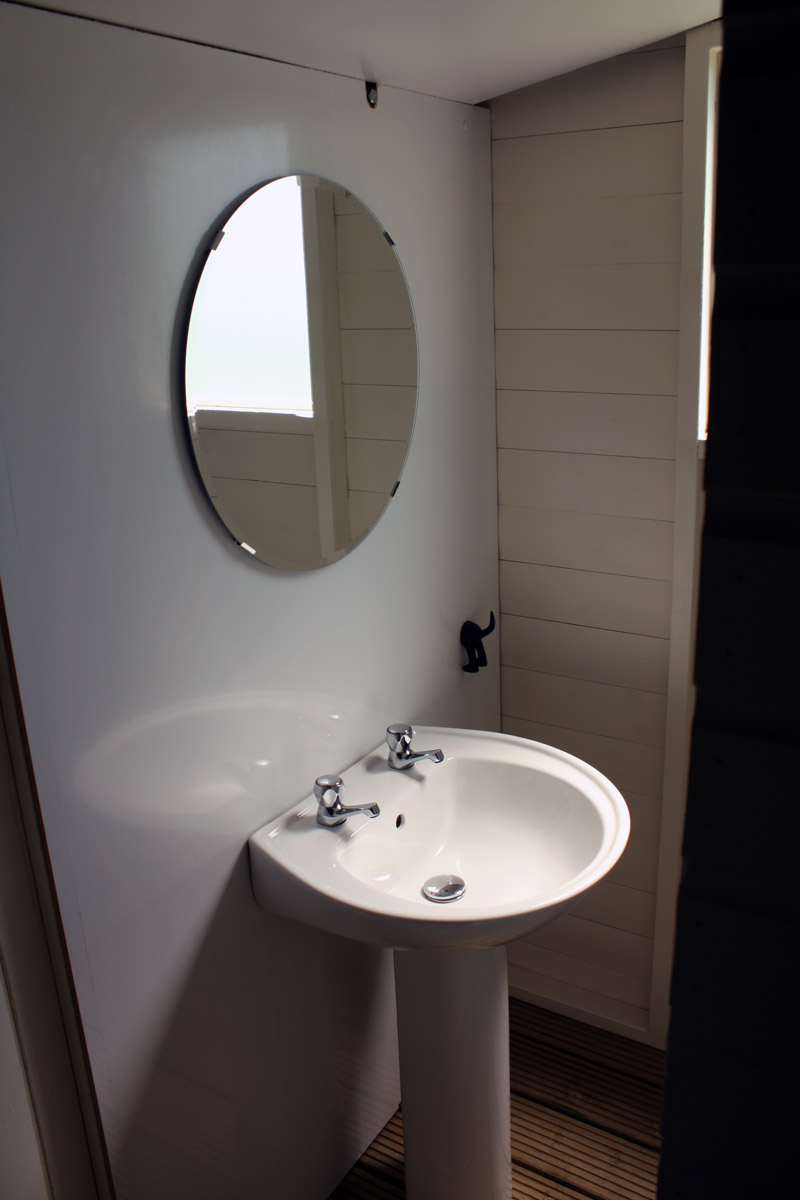 A round mirror, and a sink, there are sinks in the bathroom and shower room with a hot and cold tap