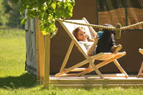 Little girl soaking in the sun in a chair outside a tent - thumbnail