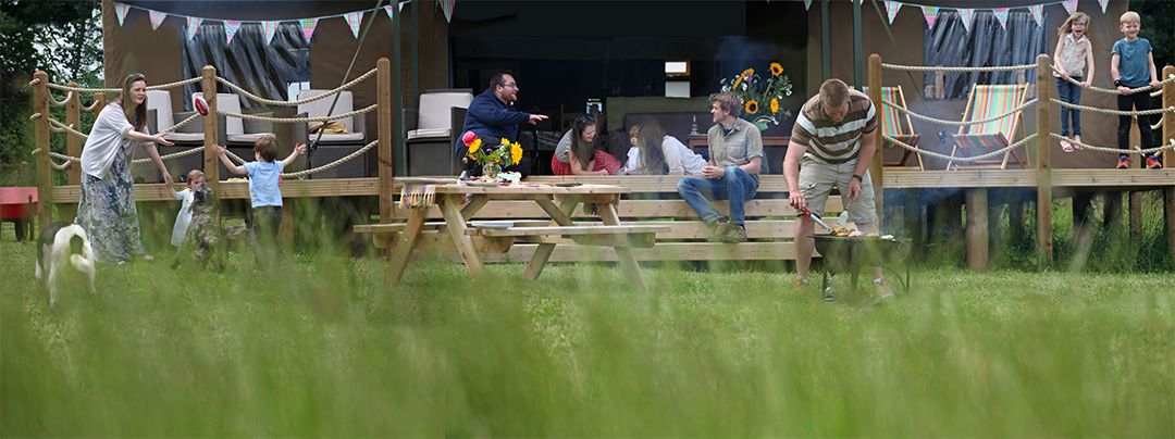 Families with kids playing games on the field outside the glamping tent
